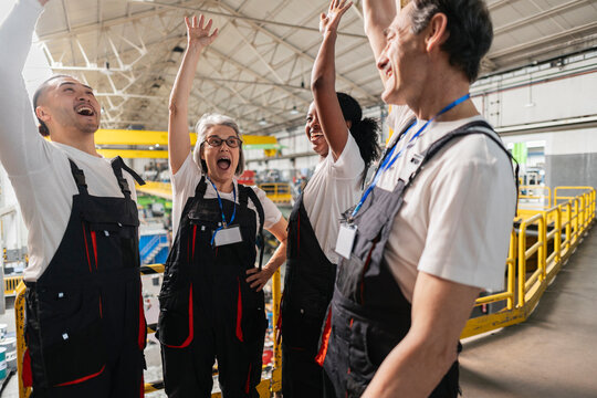 Smiling factory technicians celebrating success indoors