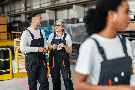 Smiling factory technicians talking on the production floor