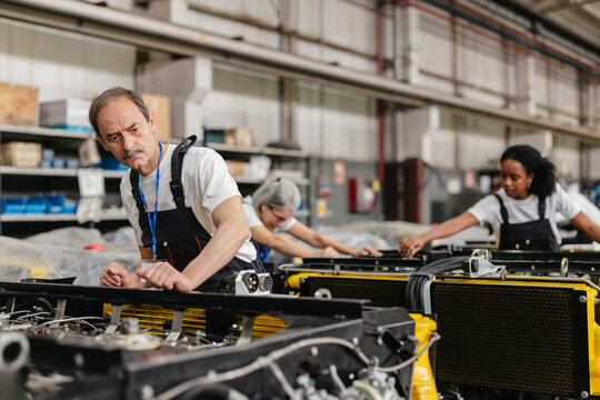 Technicians in uniform assembling engine equipment indoors
