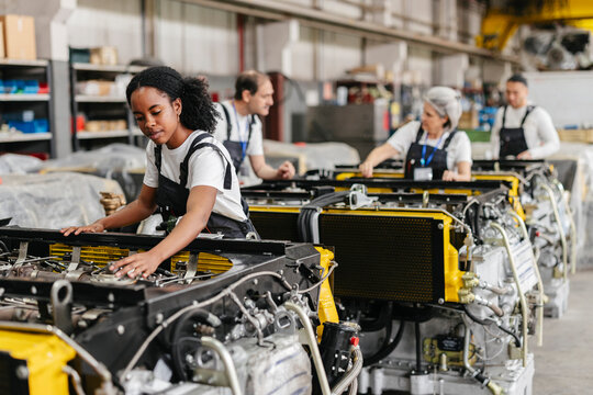 Mechanics assembling heavy machinery on production line