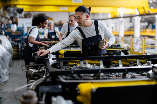 Worker assembling machinery on an industrial production line