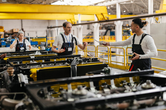 Factory workers discussing blueprint on assembly line