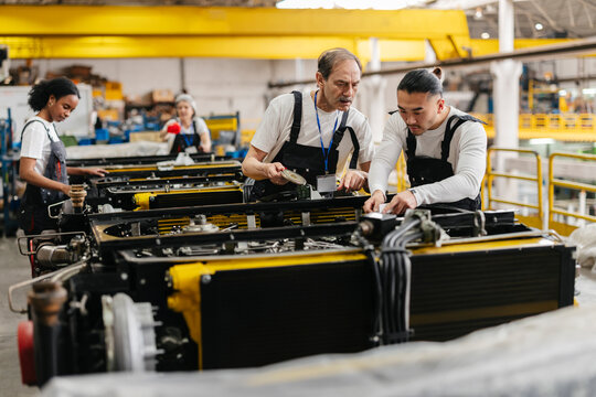 Workers assemble machinery at an industrial manufacturing plant