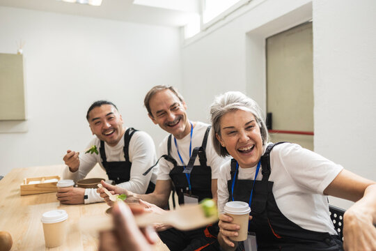 Factory workers laughing while eating lunch in the cafeteria