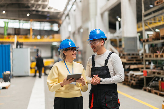 Smiling manager and engineer discussing work in a factory