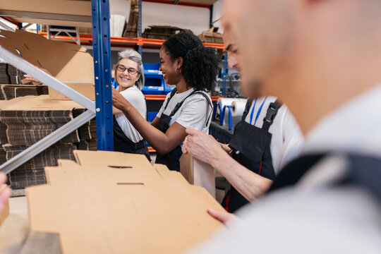 Colleagues assembling cardboard packaging indoors