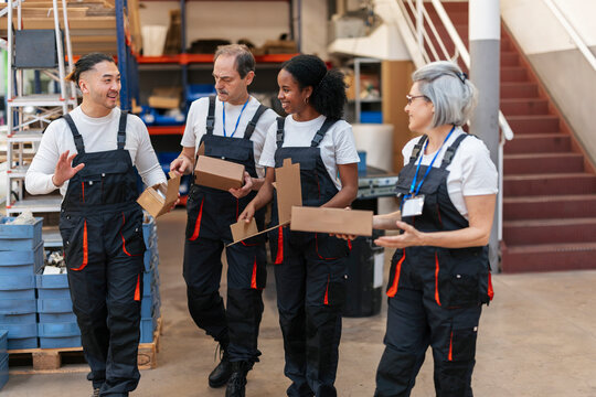 Warehouse team walking and talking with box indoor