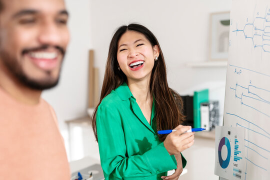 Cheerful businesswoman standing near whiteboard in office