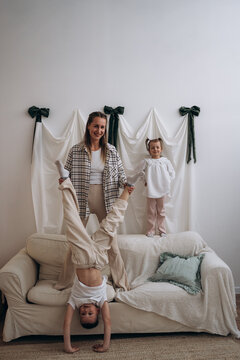 Smiling mother holding son doing handstand on living room sofa