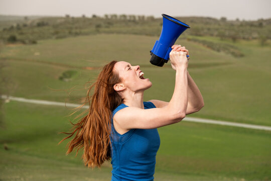 Activist in blue shirt shouting through megaphone outdoors