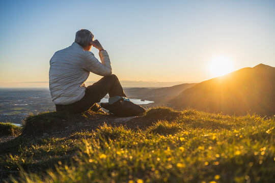Hiker relaxing outdoors on mountain grass at sunset