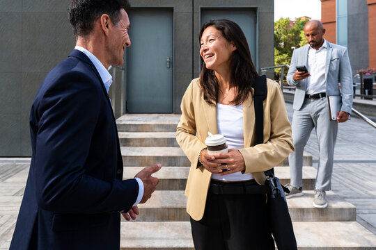 Smiling business coworkers talking on city stairs outdoors