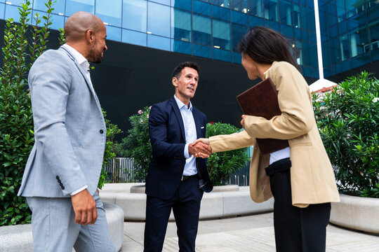 Businessman and businesswoman handshake outdoors near office building