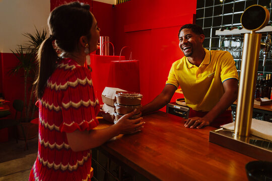Server handing takeout food to customer at restaurant