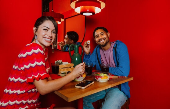 Happy couple eating sushi on a date at a red restaurant