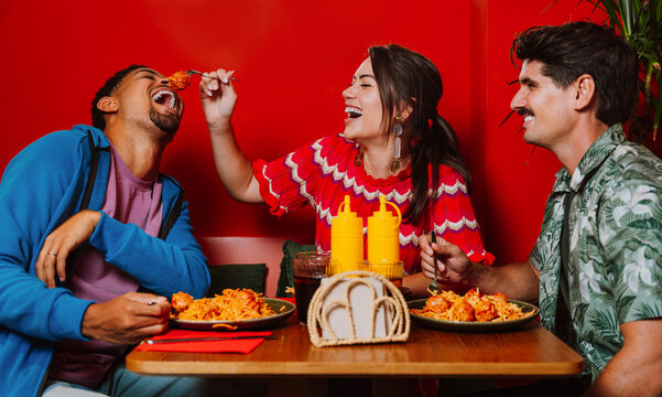 Friends laughing and sharing spaghetti dinner at a restaurant