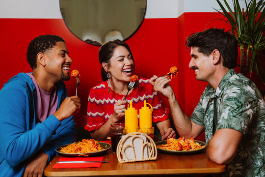 Friends eating spaghetti and meatballs together at a restaurant