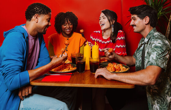 Friends laughing and eating spaghetti at a restaurant