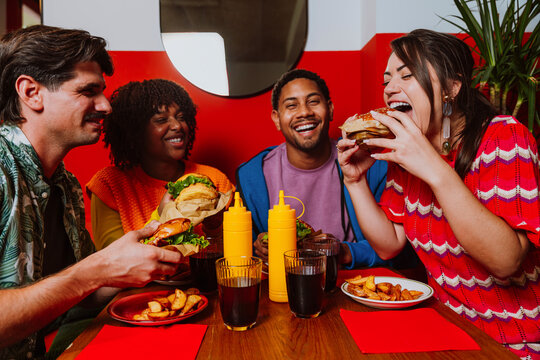 Friends eating hamburgers and laughing in a restaurant