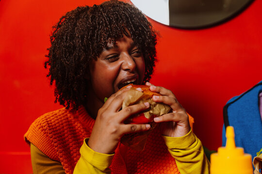 Happy customer taking a big bite of a hamburger at a restaurant