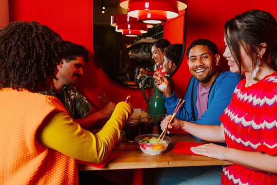 Friends eating sushi and laughing together at a restaurant
