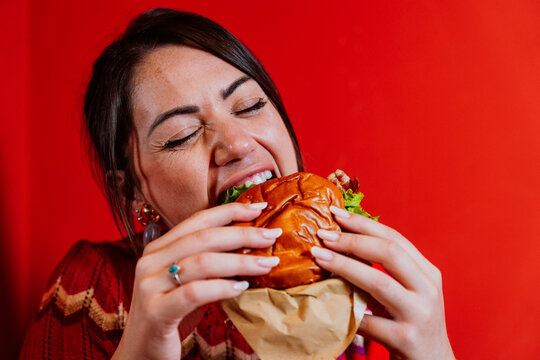 Customer enjoying a delicious burger on red background