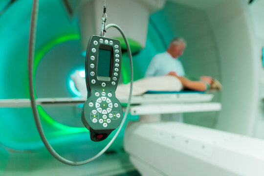 Doctor and patient in a proton therapy room with a focus on a remote control in the foreground