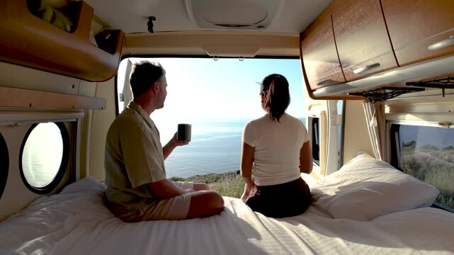 Two travelers savor a peaceful morning in their cozy camper van, gazing out at the breathtaking Chalkidiki shoreline. Coffee in hand, they relish the beauty of Greece nature.