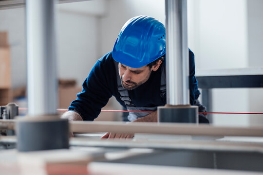 Craftsman in blue helmet working with machinery indoors