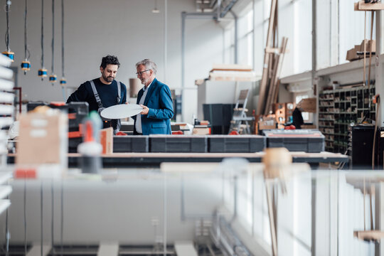 Engineer and craftsman discussing a project in a workshop