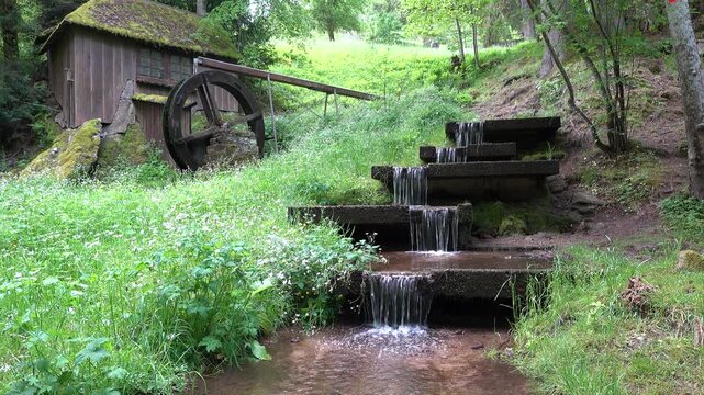 Die kleine Wasserm&uuml;hle im Kurpark von Bad Wildbad im Nordschwarzwald in Deutschland neben einer Wasserkaskade