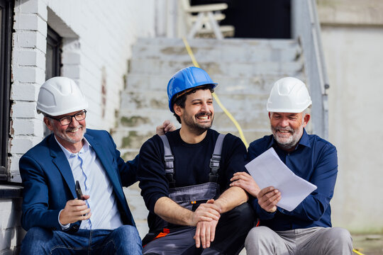 Engineer and craftsmen discussing a project outdoors with optimism