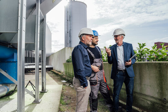 Engineers discussing a project outdoors at an industrial site