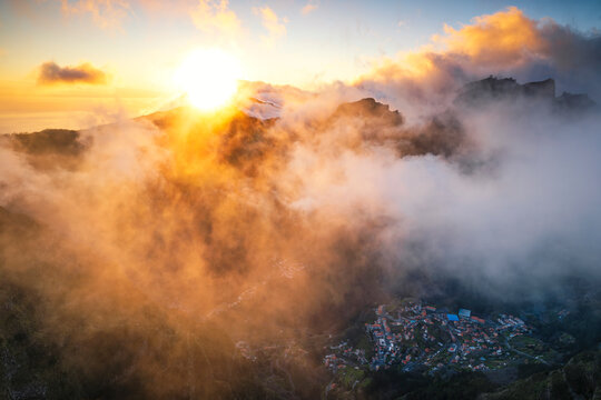 Golden sunlight and mist over mountain village in Madeira