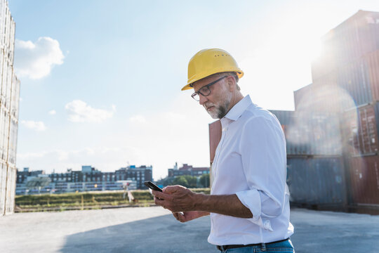 Logistics manager using smartphone at container port