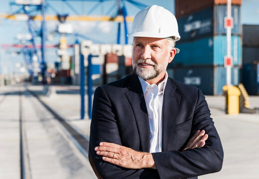 Confident logistics manager wearing helmet at outdoor shipping port