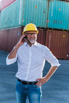 Smiling supervisor talking on mobile phone at shipping yard