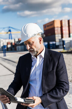 Manager with helmet reading document at shipping terminal