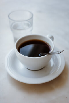 Minimalist white cup of black coffee and glass of water