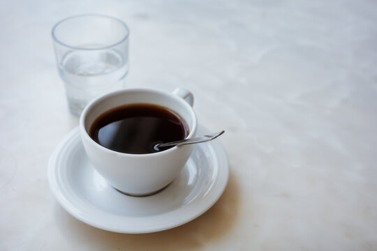 White coffee cup and glass of water on a table with copy space