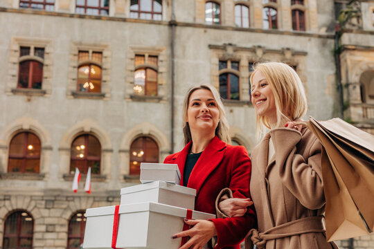 Friends with gift boxes and shopping bags in city during holiday season