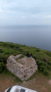 Explore ancient stone ruins perched on a cliff overlooking the tranquil Aegean Sea in Chalkidiki, Greece. Experience stunning views amidst lush greenery and serene surroundings.