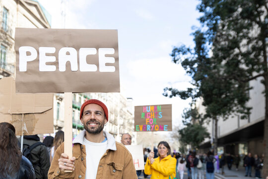 Smiling person holding peace sign during urban street protest