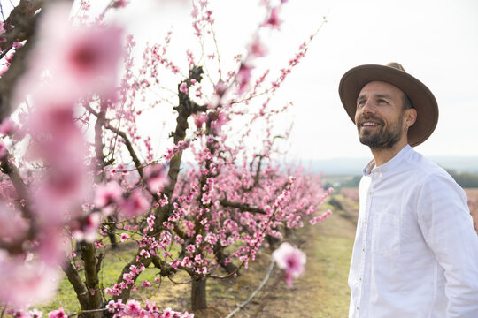 Smiling farmer with hat resting in a spring orchard in Lleida