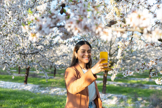 Woman taking a selfie under blooming spring trees in Lleida