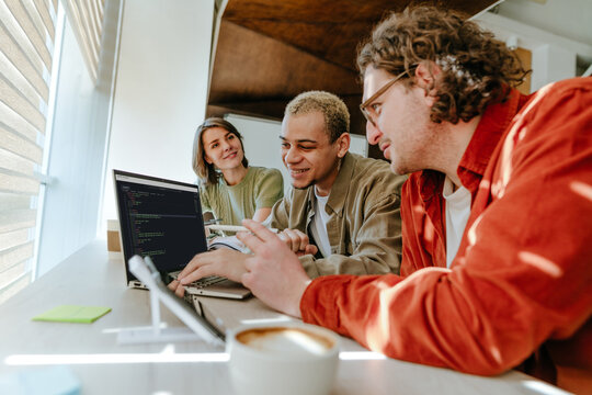 Team collaborating on code at laptop in bright office