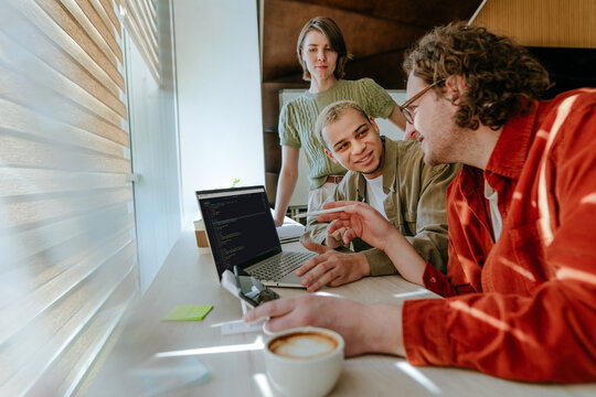 Programming team discussing code on laptop in office