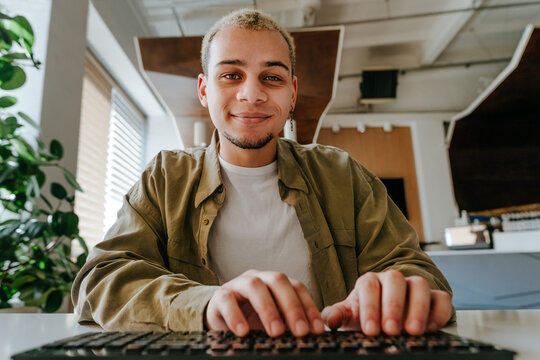 Smiling programmer typing on keyboard at the office