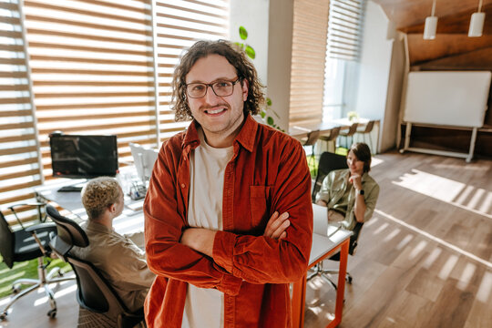 Smiling businessman standing in modern office with team
