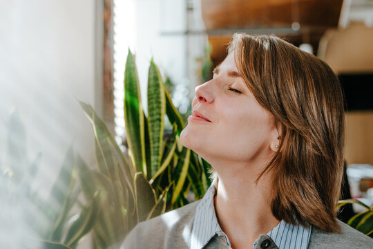 Businesswoman relaxing with eyes closed near a sunny office window